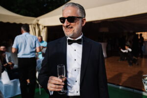 Handsome baby boomer drinking wine in a tuxedo with glasses on - ee220805