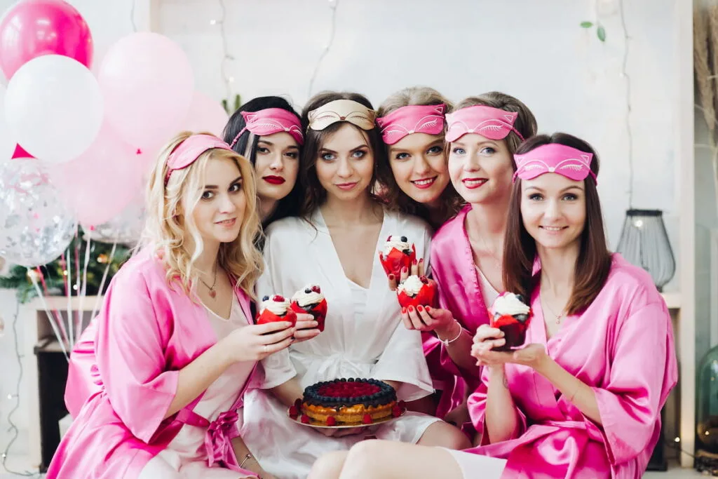Pretty girls in pink robes and sleep masks with desserts at bridal showers 