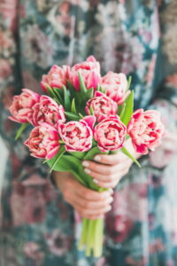 Woman in colorful dress holding bouquet of pink tulips - ee220805