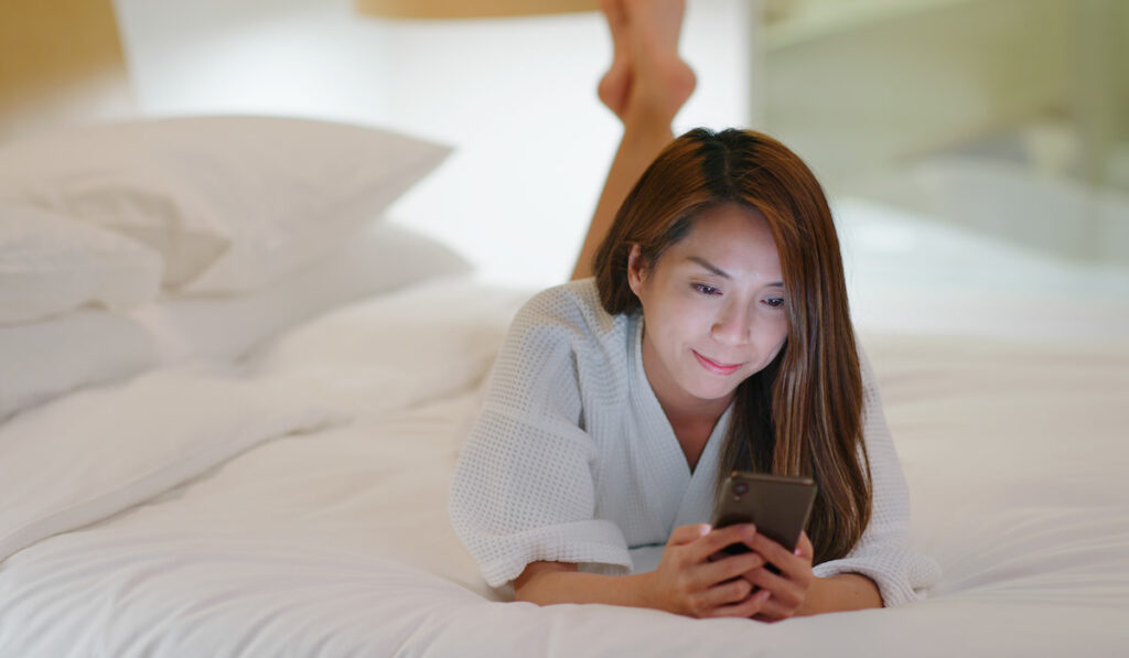 Woman use of mobile phone on bed at night before going to sleep