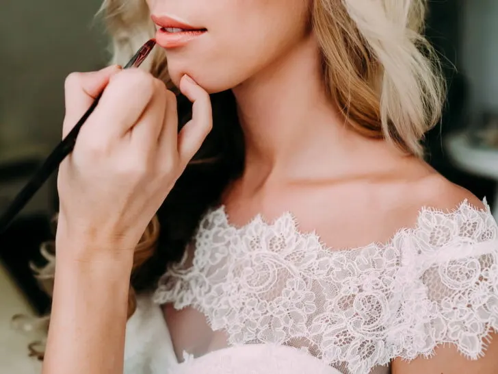 Young-beautiful-bride-applying-wedding-make-up-by-make-up-artist.-Morning-preparation.-Close-up-hands-near-face