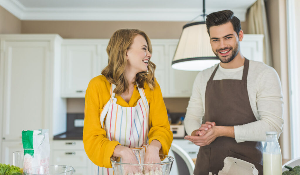 Young couple making dough in kitchen together


