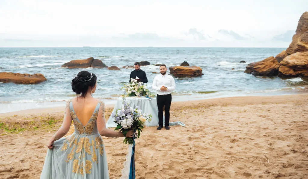 wedding couple on the ocean with a priest

