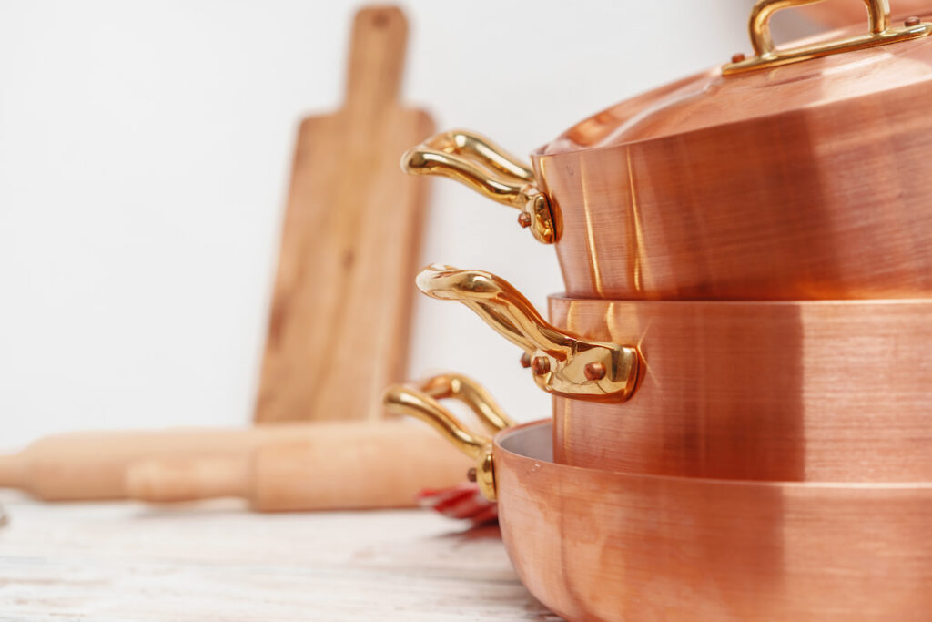 Luxury copper pots and blurry woodenboard on background in the kitchen