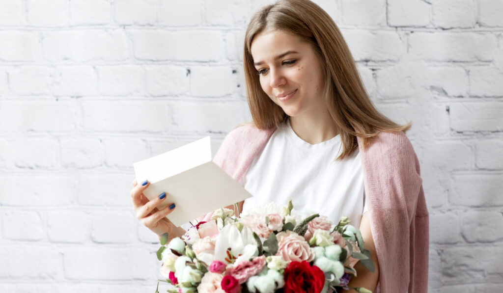Portrait of woman receiving card and bouquet of flowers