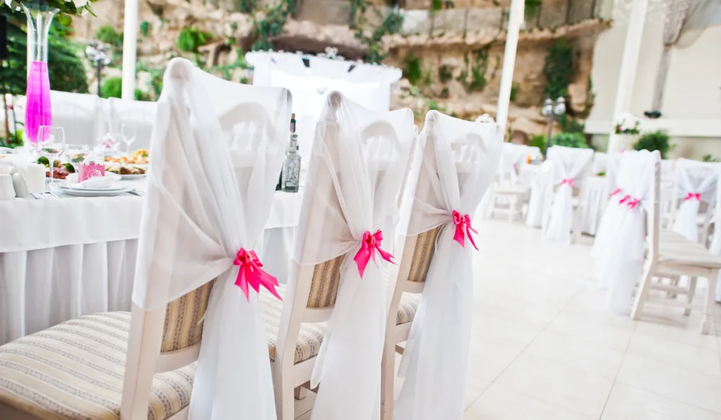 Wedding guest chairs with pink ribbons at wedding hall.
