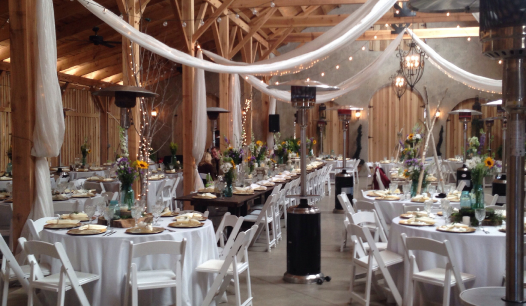Wedding reception venue inside a timber frame barn here set up
