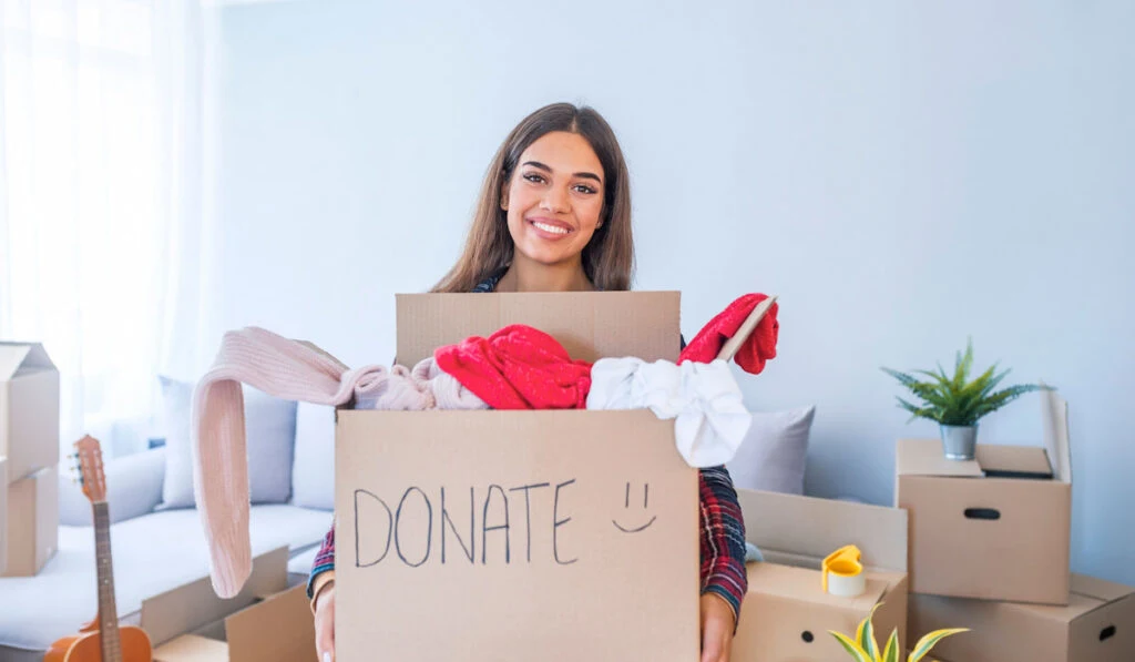 Young woman with donation box at home. 