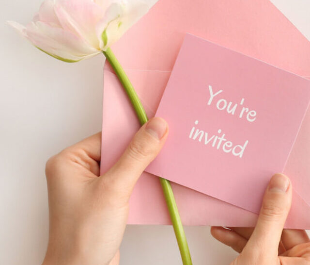 cropped-Female-hands-with-pink-invitation-and-pink-flower-on-white-background-ss220902.jpg