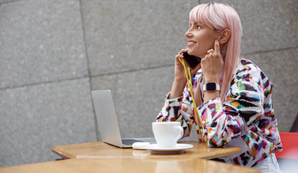 lady with pink dyed hair having a conversation on smartphone on wrist strap outdoors