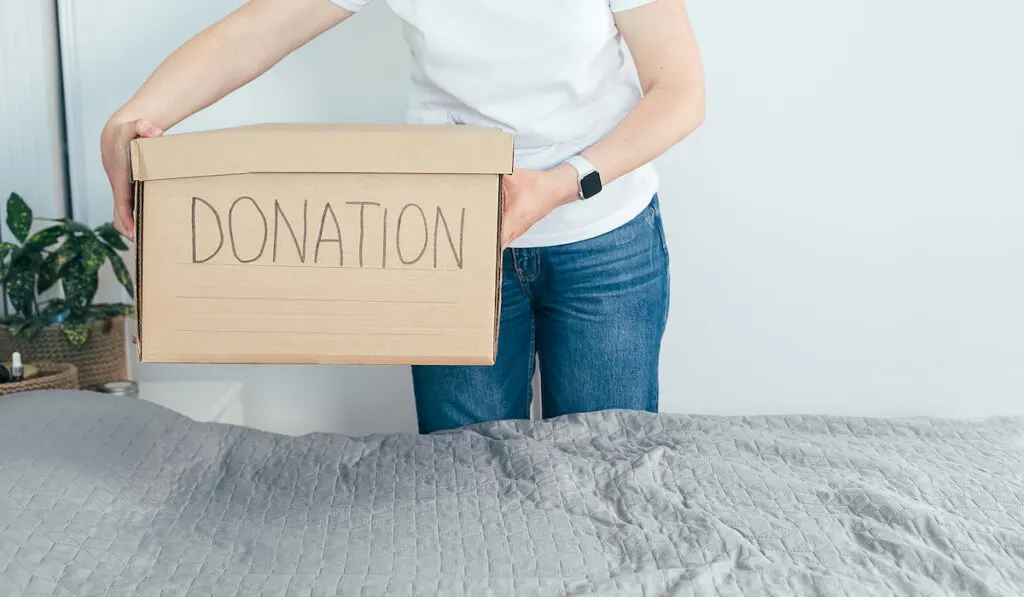 woman holding a donation box with her old stuffs 