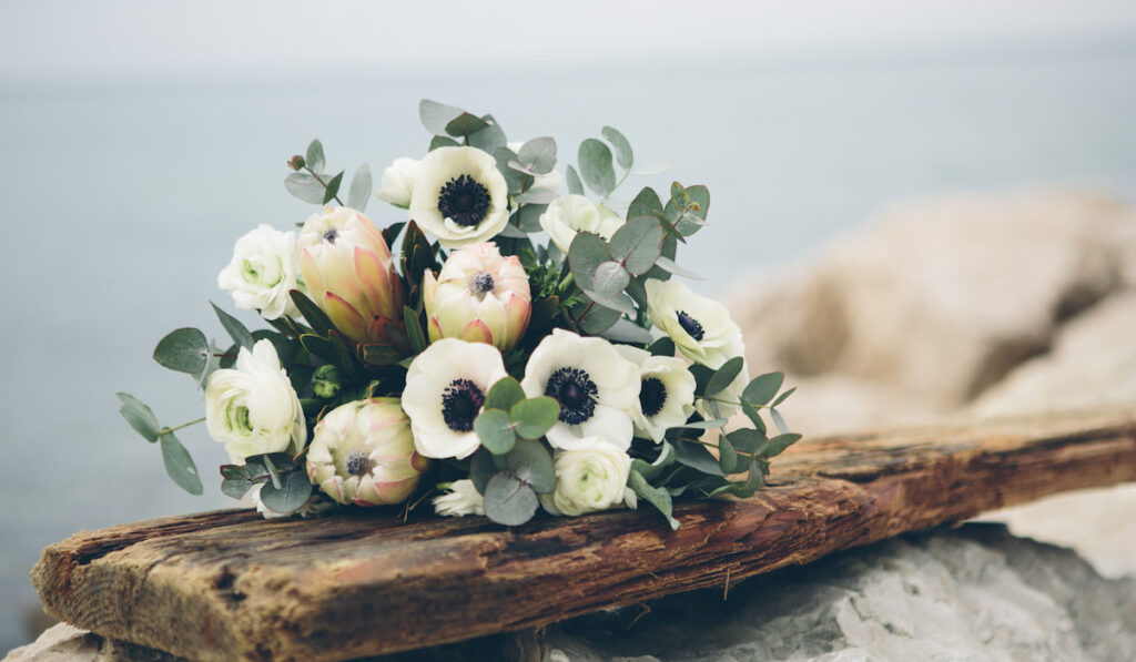 Bouquet of anemone flowers with green leaves on a wooden board 