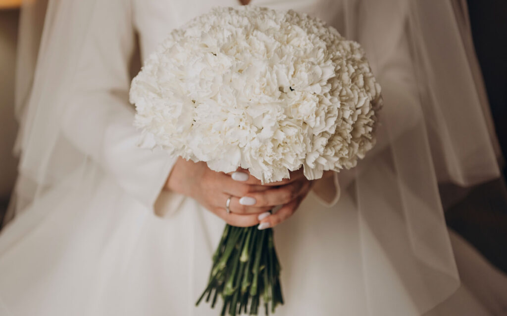 Bride holding a bouquet of white carnations 