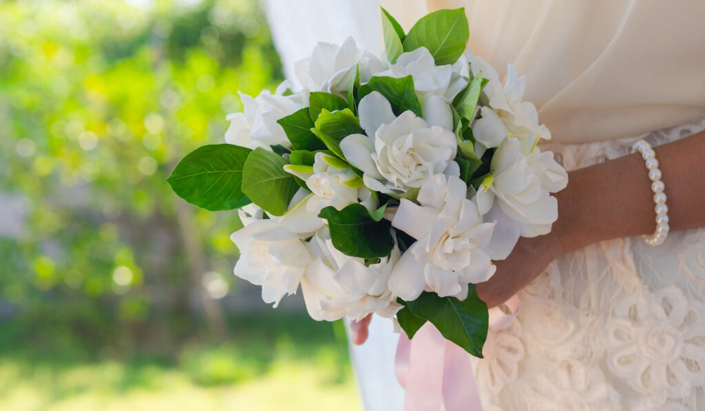 Bride holding gardenia bouquet flowers on outdoor wedding ceremony