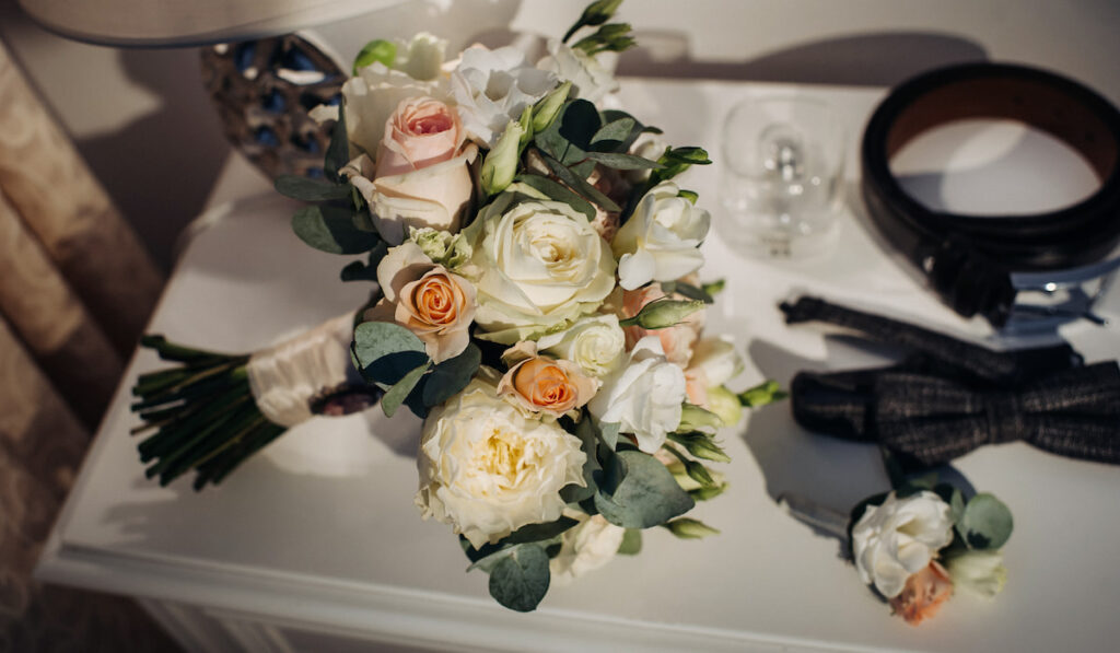 Wedding bouquet of roses with boutonniere and belt on the table