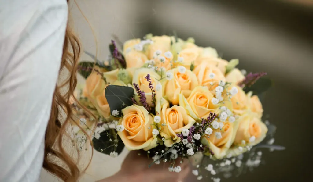 Bride holding her wedding bouquet of yellow roses