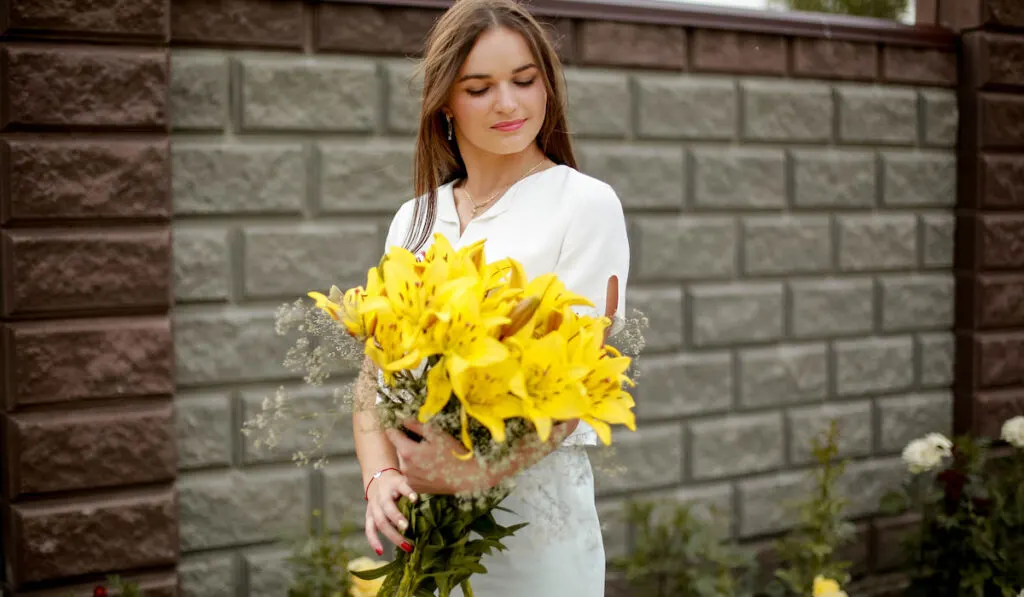 Woman holding a bouquet of yellow lilies