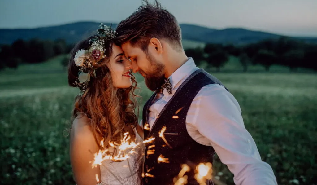 bride and groom with sparklers on a meadow 