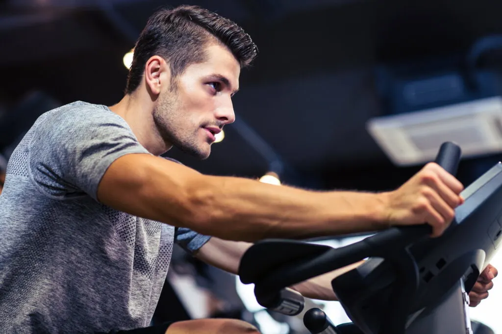 Side view portrait of a man workout on a fitness machine at gym