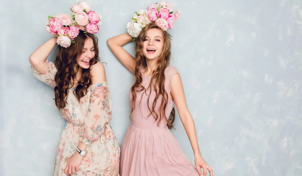 Two beautiful girls wearing silk floral dress holding flower 