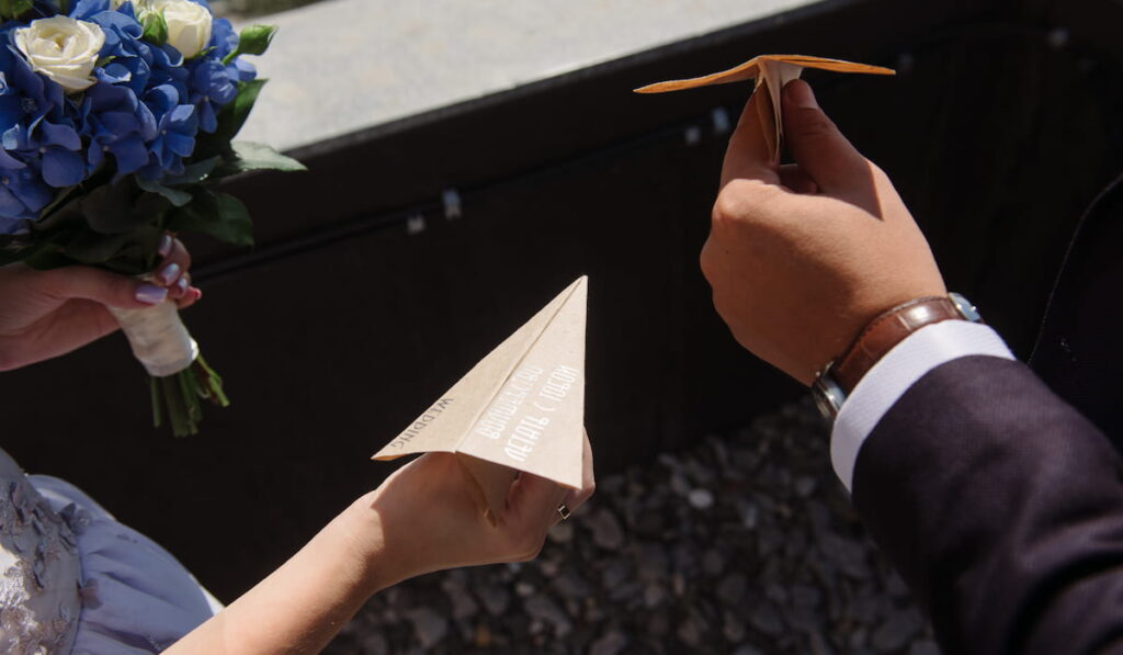 couple launching paper planes from the roof