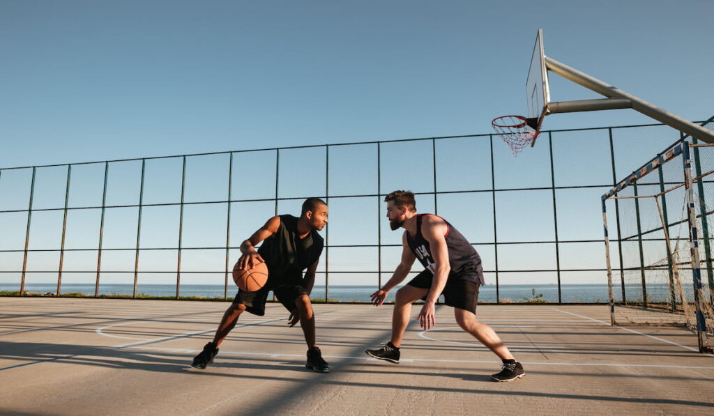 two young men playing basketball at the playground 