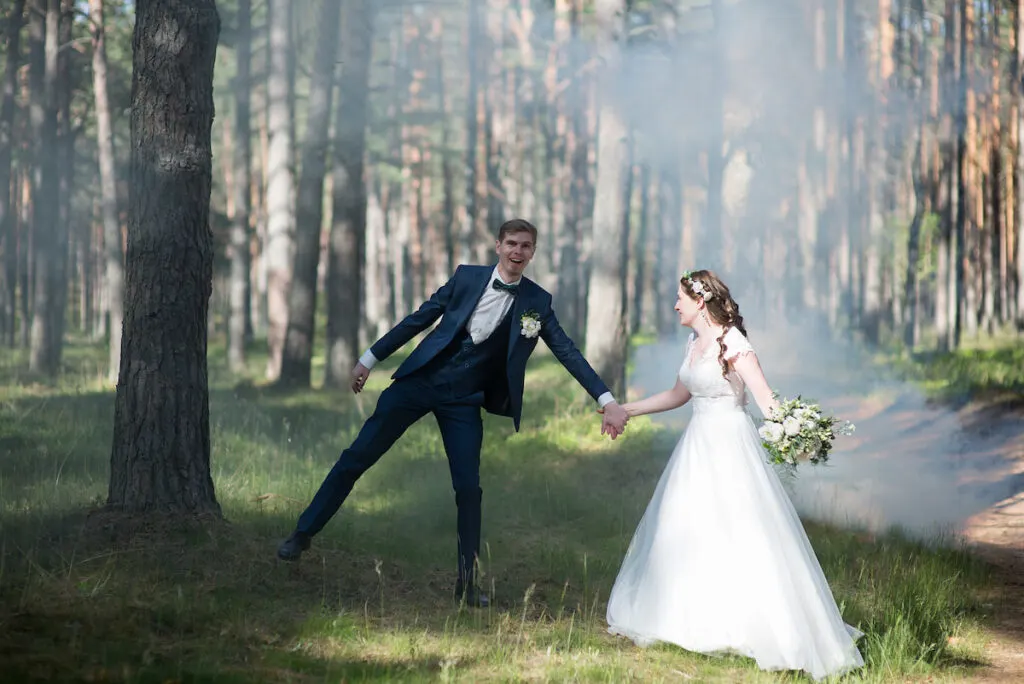 groom and bride in the woods hold hands together