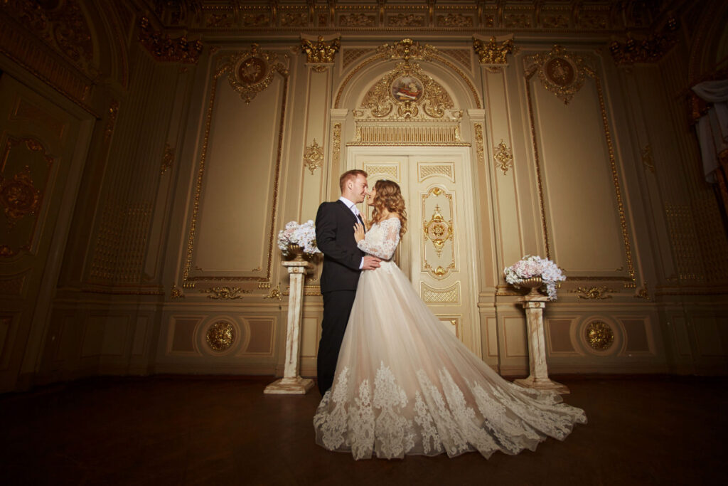 newly wed couple wearing tuxedo and flowing ball gown in an elegant background